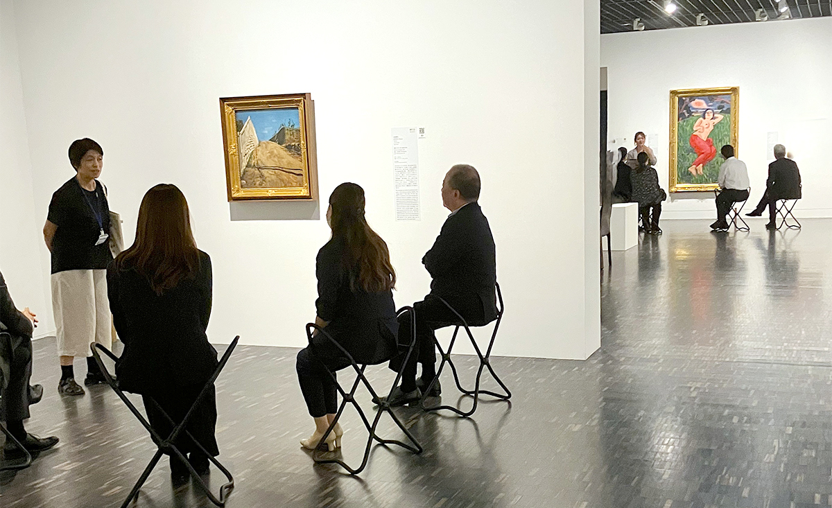 美術館研究員のファシリテートのもと少人数グループで作品に向き合う参加者 （写真左：岸田劉生《道路と土手と塀（切通之写生）》、写真右：萬鉄五郎《裸体美人》におけるプログラムの様子）